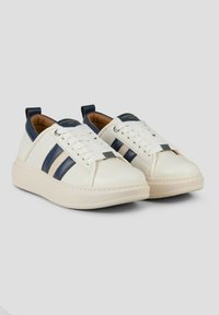 Sneakers in pelle bianca con strisce blu navy e suola beige. Caratteristiche includono una punta arrotondata, lacci piatti e linguette sul tallone.