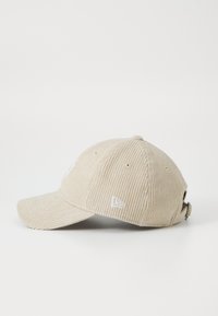 Beige cordbársony baseball sapka, ívelt csúccsal, hímzett logóval és állítható pánttal a hátán a személyre szabott illeszkedésért.