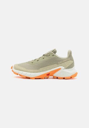 Chaussure de trail beige et orange avec semelle texturée, lacets et logo Salomon sur le côté, montrée de profil droit.