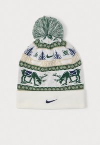 Zimska kapa z zelenim pom-ponom, vzorci jelenov in dreves, napis "JUST DO IT." ter mornarsko modri Nike znak na belem prepognjenem robu.