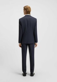 Marinblå skräddarsydd kostym med slim fit, som har ett texturerat tyg och subtilt rutmönster. Inkluderar en vit skjorta under.
