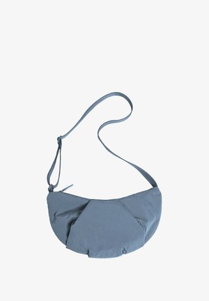 Šedá textilní krosbody taška s zaobleným tvarem, která má na přední straně řasený design a tenký nastavovací popruh. Zapínání na zip nahoře.