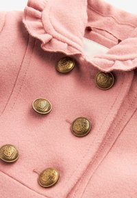 Pink wool coat with ruffled collar, featuring six decorative brass buttons, stitched detailing, and a smooth texture.