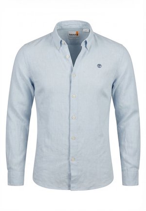 Chemise bleu clair à manches longues avec boutons, col boutonné et logo Timberland sur la poitrine gauche, présentée sur fond blanc.