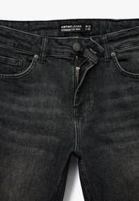 Czarne dżinsy o prostym kroju wykonane z materiału dżinsowego. Posiadają zamek błyskawiczny, zapięcie na guzik oraz design z pięcioma kieszeniami. Metka: Koton Jeans, W 32, L 32.