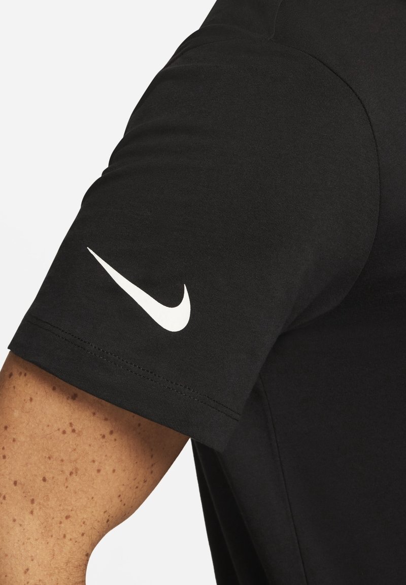 Black short-sleeve t-shirt with a smooth texture and a white Nike swoosh logo on the left shoulder. Features clean stitching and fitted design.