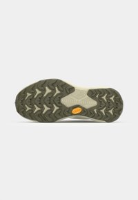Gumijasti zunanji podplat čevlja z teksturiranim vzorcem, ki vključuje rumen logo Vibram in kombinacijo temno zelene in bež barve.