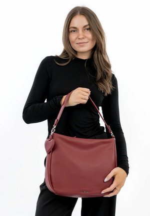 Sac à main en cuir rouge avec une finition texturée, arborant un accent en forme de cœur et une bandoulière robuste. Forme rectangulaire, taille moyenne.