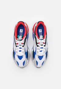 Sportowe sneakersy z białą siateczkową cholewką z niebieskimi i czarnymi akcentami, czerwonym wnętrzem oraz teksturowaną szaro-skalną podeszwą. Wyróżniające się zapięcie na sznurowadła.