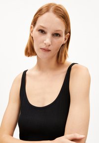 Black ribbed tank top with a scoop neckline, thin straps, and a fitted design, showcasing smooth texture and minimal detailing.