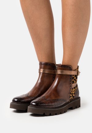 Bottines marron avec un effet crocodile, des panneaux à imprimé léopard, des accessoires en bronze et une semelle épaisse. Perforations décoratives sur le bout.