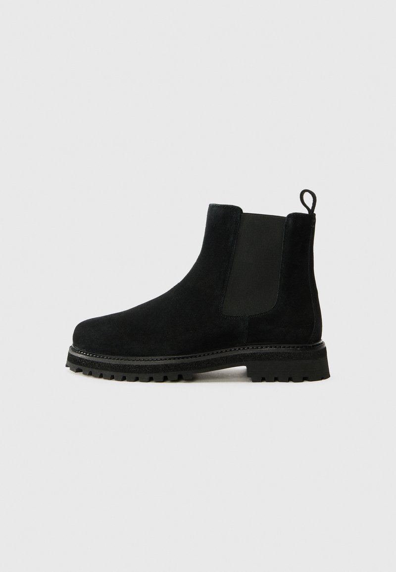 Botas Chelsea negras de ante. Cuentan con paneles elásticos en los laterales y una lengüeta. Suela gruesa de goma con un tacto texturizado.
