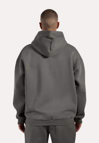 Grauer Kapuzenpullover mit großer Kapuze, gerippten Bündchen und Saum. Das Design ist locker geschnitten mit einer glatten Textur und einem minimalistischen Ästhetik.