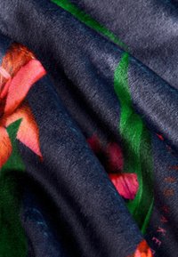 Pehme, tumesinine kangas, millel on roosade ja roheliste lillemotiividega muster. Tekstuur on sametine ja sile, rikkaliku sametise pinnaga.