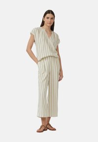 Ensemble deux pièces rayé en beige et crème, comprenant un haut ample à manches courtes et un pantalon droit à coupe décontractée.