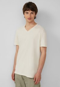 Lichtbeige V-hals t-shirt gemaakt van zachte stof, met korte mouwen en een relaxed fit. Minimalistisch ontwerp zonder opvallende patronen of logo's.