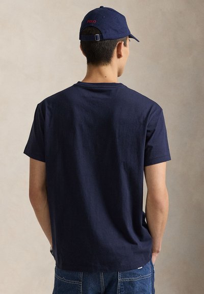 Mornarski pamučni T-shirt kratkih rukava, okruglog vrata i opuštenog kroja, nošen s odgovarajućom mornarskom kapom na kojoj je crvenim slovima ispisano "POLO".