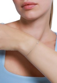 Silberner minimalistischer Armreif mit einem einzelnen Perlenakzent, der ein dünnes, elegantes Design aufweist und an einem hellhäutigen Arm vor einem schlichten Hintergrund getragen wird.