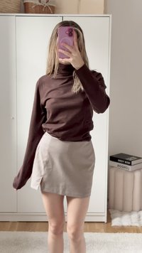 Pull en cachemire marron à manches longues associé à une mini-jupe à motifs avec une fente sur le côté. Design simple avec des couleurs neutres et des textures douces.