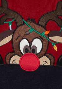 Suéter rojo de punto con un reno bordado que tiene una nariz roja redonda, ojos negros y astas decoradas con luces coloridas.