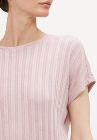 Top de manga corta de color rosa claro con textura acanalada horizontal y un escote redondo, confeccionado en una tela suave y ligera.
