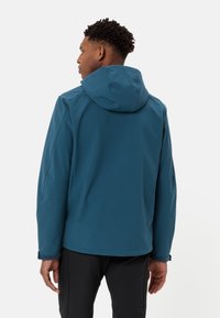 Męska niebieska kurtka softshell z kapturem, o eleganckim designie, gładkiej fakturze i regulowanych mankietach. Brak widocznych logo lub wzorów.