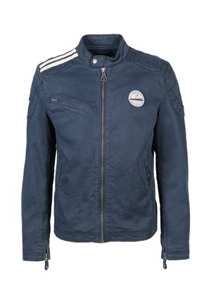 Chaqueta azul marino con cremallera y cuello alto, rayas blancas en los hombros, un parche en el pecho y bolsillos con cremallera en la parte delantera y en las mangas.