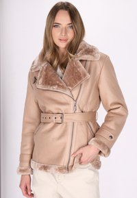 Giacca in ecopelle beige con colletto in pelliccia marrone morbida, vita con cintura, frontale con zip e maniche texturizzate. Dettagli in metallo argentato.