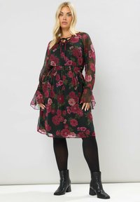 Vestito midi floreale con sfondo nero, caratterizzato da fiori borgogna e verdi, vita elastica, maniche lunghe trasparenti e orlo arricciato.
