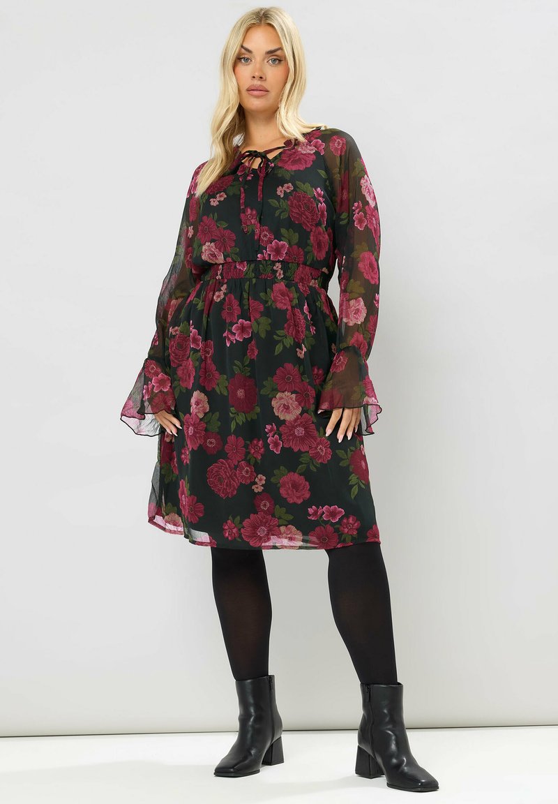 Vestito midi floreale con sfondo nero, caratterizzato da fiori borgogna e verdi, vita elastica, maniche lunghe trasparenti e orlo arricciato.