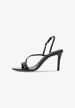 Sandalo nero con tacco alto a spillo, sottili cinturini, chiusura con fibbia e tacco appuntito, su sfondo bianco.