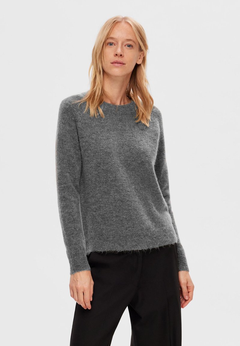 Grå, langærmet sweater lavet af blødt, fluffy materiale med rund udskæring og en let løs pasform, parret med sorte bukser.