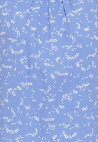 Tissu bleu clair avec un motif floral de petites fleurs blanches. Le design présente des fleurs éparpillées et des éléments texturés subtils.