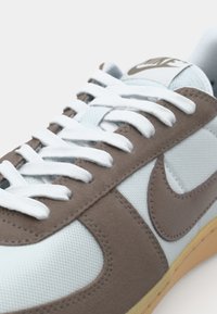 Svijetloplavi tenisice s smešnim aneksima od suede kože, bijelim vezicama i smešnim Nike logom. Imaju teksturiranu gornjište i gumeni potplat.