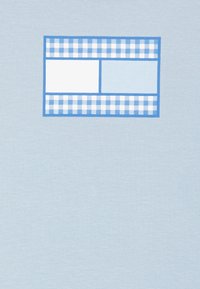 Błękitna koszulka z krótkim rękawem z prostokątną grafiką podzieloną na dwie sekcje: jedna jest biała, a druga jasnobłękitna, otoczona niebiesko-biała kratką.