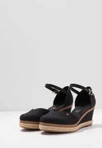 Scarpe con zeppa nere con parte superiore in tela, punta a forma di mandorla, cinturino alla caviglia regolabile e piattaforma in juta intrecciata. Accentuate con un piccolo logo.
