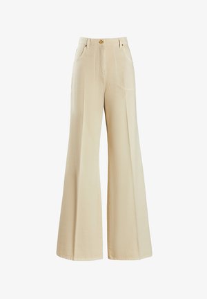Pantalons larges beiges en tissu texturé, avec des poches avant et une fermeture à bouton doré à la taille.