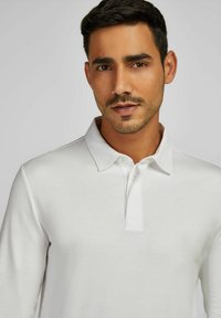 Weißes Langarm-Polohemd mit einem Kragen, zwei Knöpfen und einer glatten Textur, das Einfachheit und ein klassisches Design hervorhebt.