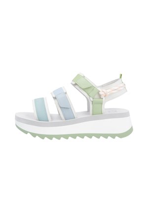 Sandales à lanières avec des bandelettes élastiques vert clair, bleues et blanches, une semelle épaisse en plateforme blanche et un fond texturé vert menthe.