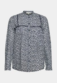 Blouse à manches longues avec boutons, motif floral petit noir et blanc et détails de coutures verticales sur poitrine et épaules.