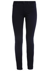 Jeans skinny in denim indigo scuro. Presentano una silhouette aderente, design a cinque tasche standard, passanti per cintura e una patta con zip e chiusura a bottone.