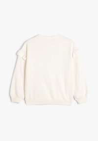 Sudadera color crema con acentos de volantes en las mangas, cuello redondo y puños elásticos. Tejido suave con una textura lisa.