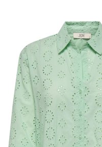 Mint green blouse with a button-up collar. Features eyelet cut-out patterns throughout, with floral shapes and a soft texture.