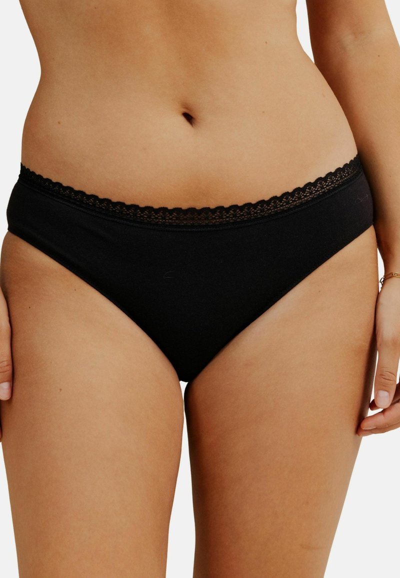 Sous-vêtements en coton noir avec une bordure en dentelle festonnée sur la taille, présentant un design simple et une texture lisse.
