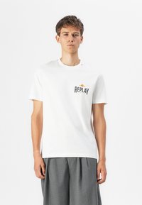 Hvit bomull T-skjorte med svart "REPLAY" logo på brystet og en liten logo på skulderen. Klassisk rund hals-design.