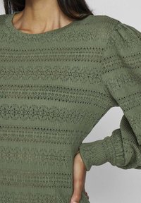 Olivgrüner Strickpullover mit rundem Ausschnitt, der strukturierte horizontale Streifen und puffärmel zeigt und ein offenes Strickmuster präsentiert.