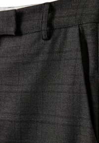 Pantalon en tissu gris foncé avec motifs à carreaux subtils, passants de ceinture et pli avant visible en gros plan.