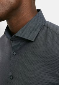 Schwarzes strukturiertes Hemd mit Knopfleiste und Rautenmuster, ausgestattet mit spitzem Kragen und einem glatten Stofffinish.