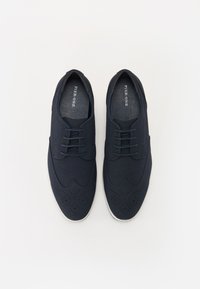 Námornické modré šnurovací boty s hladkým textilním svrškem, designem typu wingtip, perforovanými detaily a bílou gumovou podrážkou.