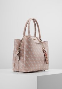 Brudnopudrowa torebka z teksturową powierzchnią i białym wzorem logo. Posiada podwójne uchwyty, zamek błyskawiczny oraz różową metalową zawieszkę.